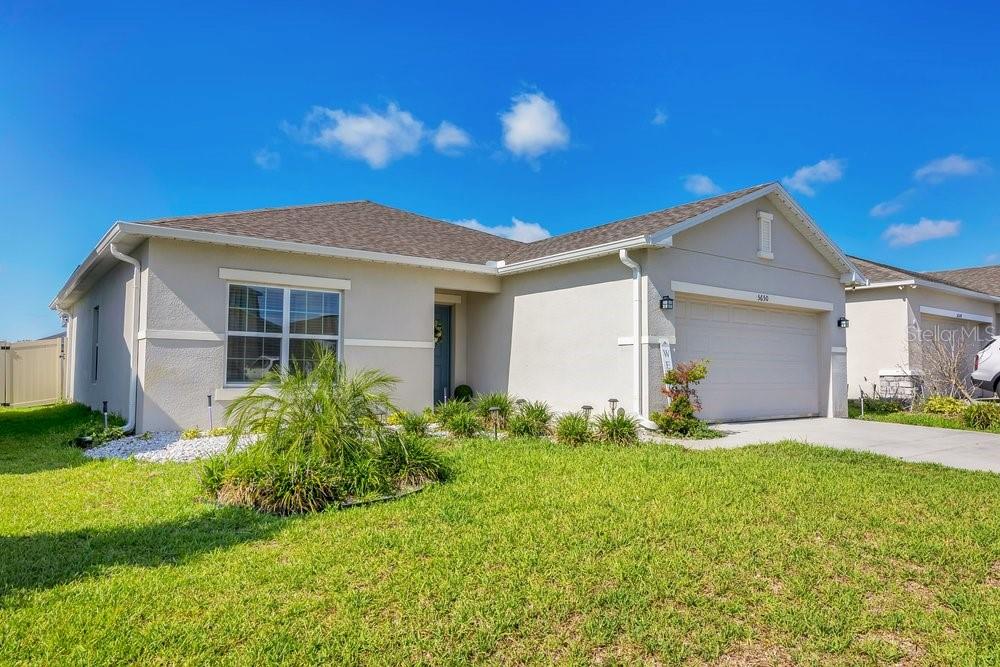 A single-story suburban house with a light-colored stucco exterior and a two-car garage — 5650 COSTA BLANCA WAY, DAVENPORT, FL