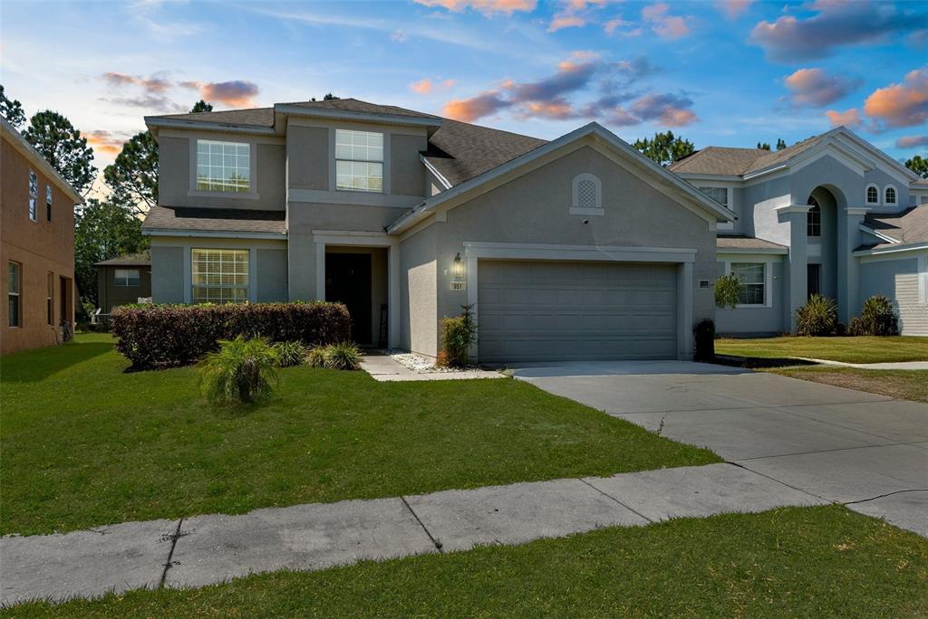 A two-story suburban house with a gray stucco exterior, a two-car garage, and a lawn — 951 NODDING SHADE DRIVE, BROOKSVILLE, FL