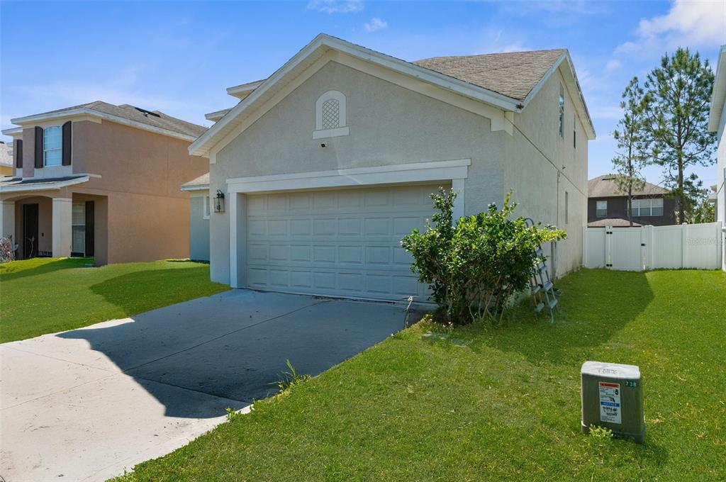A beige two-story house with a front-facing garage and a green lawn — 951 NODDING SHADE DRIVE, BROOKSVILLE, FL