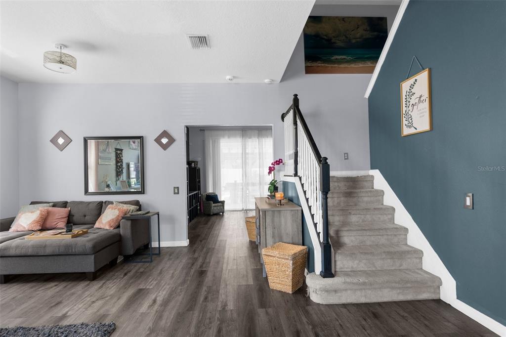 A living room features a grey sectional sofa, a staircase with carpeted steps, and wood flooring — 951 NODDING SHADE DRIVE, BROOKSVILLE, FL
