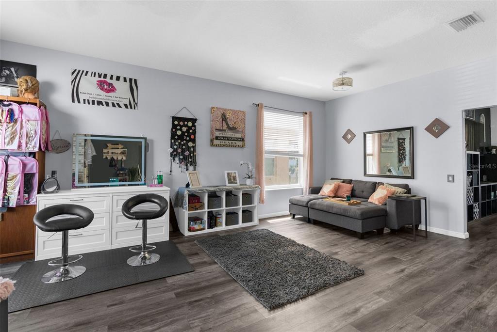 A studio room features a makeup vanity, a gray sectional sofa, and wood-look flooring — 951 NODDING SHADE DRIVE, BROOKSVILLE, FL