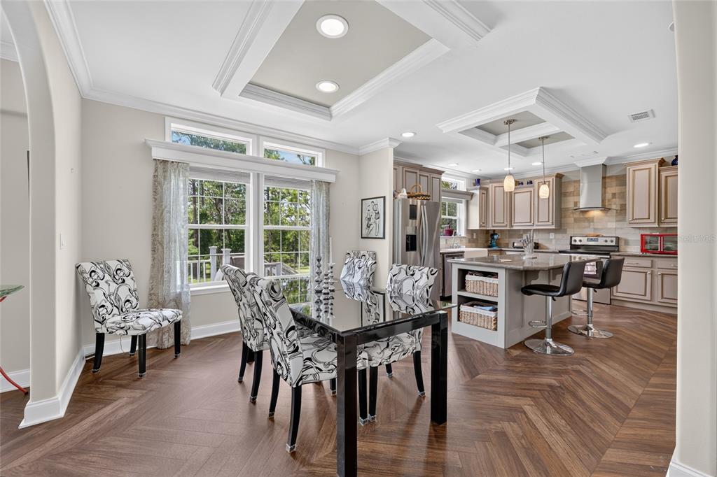A dining area with a glass table and patterned chairs opens into a modern kitchen — 7131 NE 138TH TERRACE, WILLISTON, FL