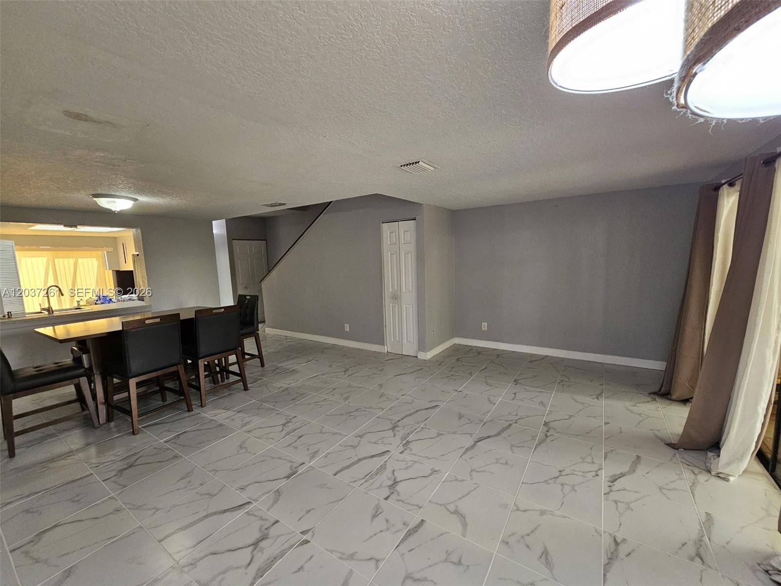A dining area features marble-look tile flooring, a breakfast bar with stools, and gray walls — 8837 NW 48th St, Sunrise FL 33351, SUNRISE, FL