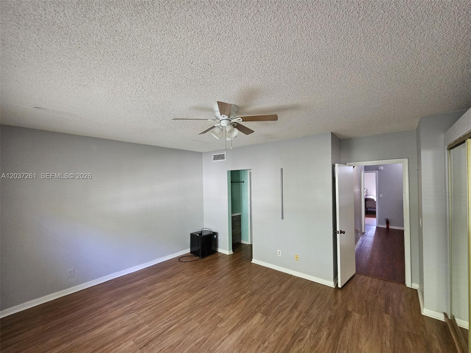 A bedroom with gray walls, wood-look flooring, a ceiling fan, and an open doorway — 8837 NW 48th St, Sunrise FL 33351, SUNRISE, FL