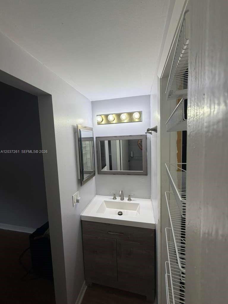 A small bathroom features a modern vanity, a rectangular mirror, and a four-bulb light fixture — 8837 NW 48th St, Sunrise FL 33351, SUNRISE, FL