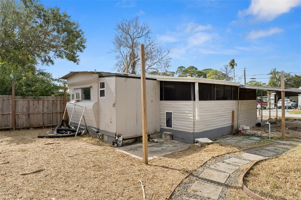 The exterior of a mobile home features a screened-in porch and a fenced yard — 7436 VAGABOND DRIVE, NEW PORT RICHEY, FL
