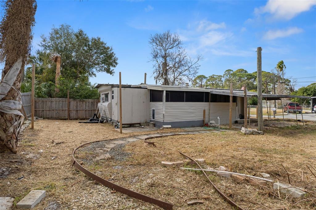 A mobile home with a screened porch and metal carport sits on a dry lot — 7436 VAGABOND DRIVE, NEW PORT RICHEY, FL