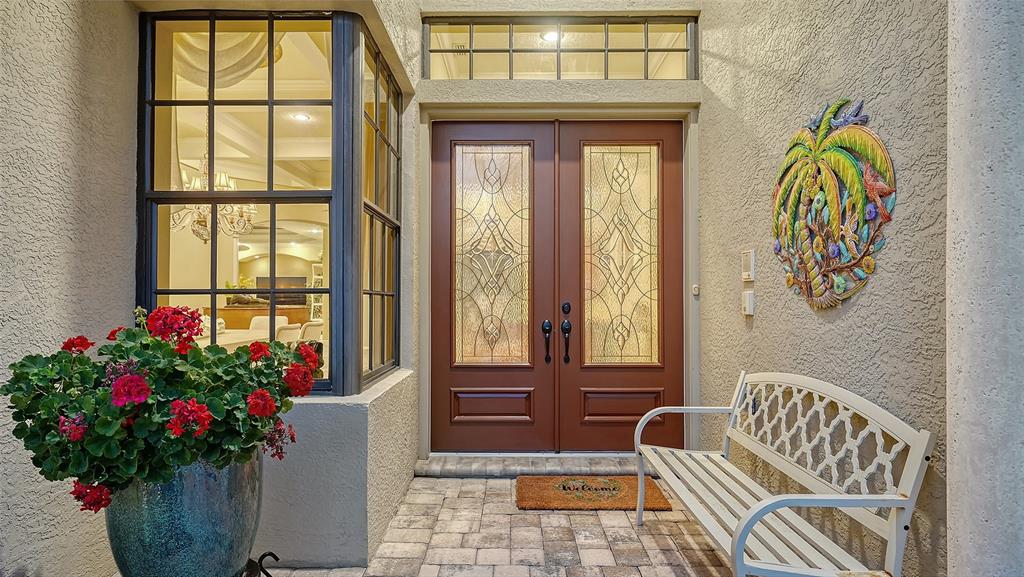 A front entryway features double doors with glass inserts, a white bench, and a potted plant — 8889 ENCLAVE COURT, SARASOTA, FL