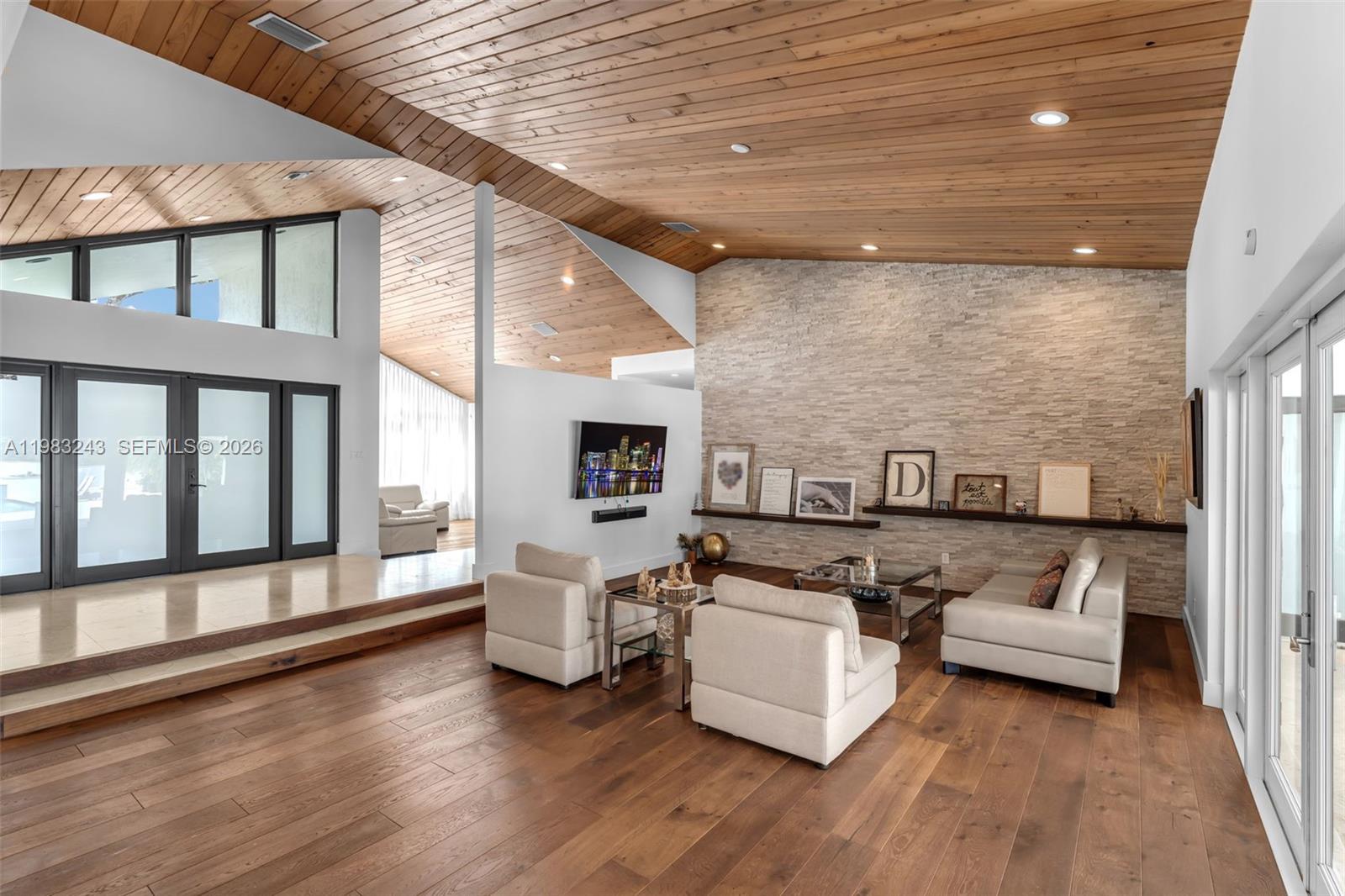 A living room features a stone accent wall, wood-paneled vaulted ceilings, and hardwood flooring — 8967 SW 117th St, Miami FL 33176, MIAMI, FL