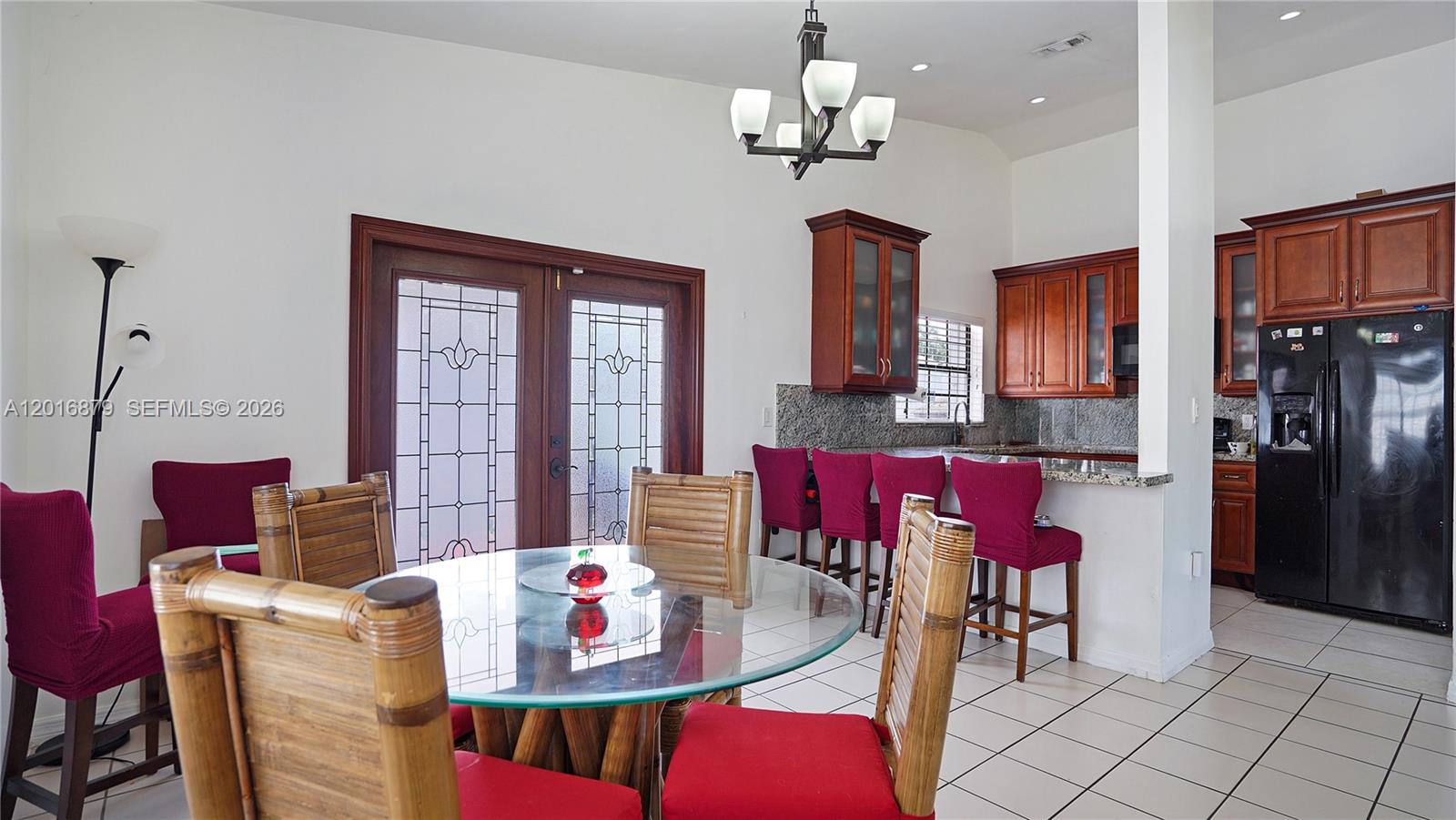 A dining area with a glass table and bamboo chairs sits beside a kitchen counter — 13755 SW 19th Ter, Miami FL 33175, MIAMI, FL