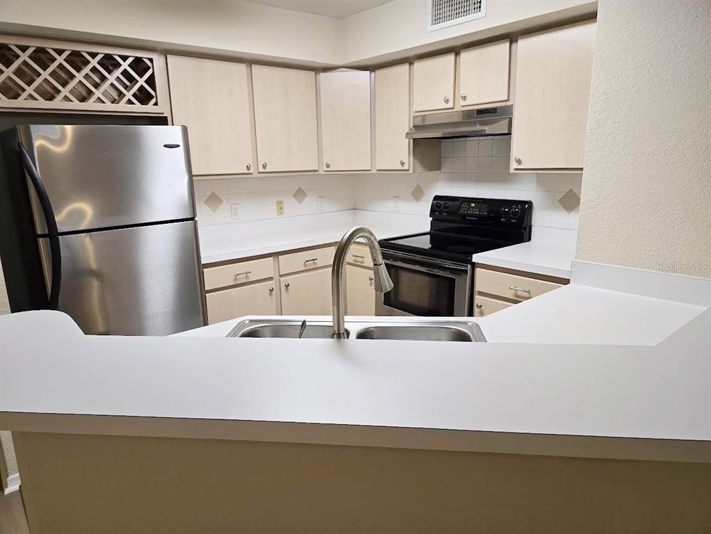 A kitchen features light wood cabinets, stainless steel appliances, and a white countertop — 831 CAMARGO WAY UNIT 109, ALTAMONTE SPRINGS, FL