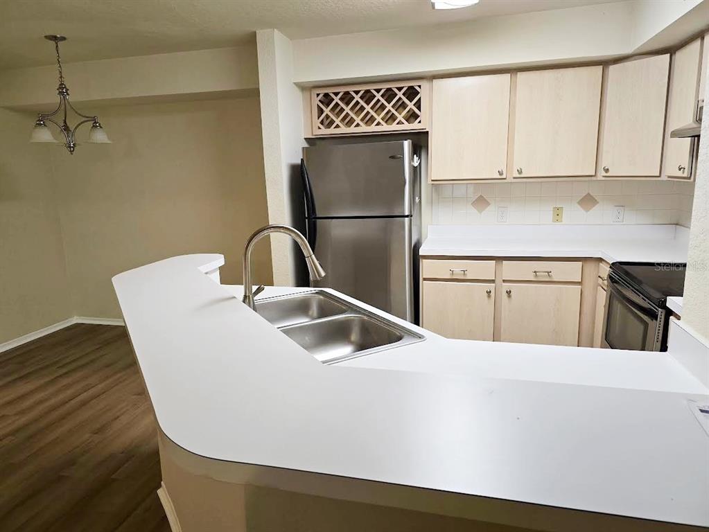A kitchen with light wood cabinets, stainless steel appliances, and a white laminate breakfast bar — 831 CAMARGO WAY UNIT 109, ALTAMONTE SPRINGS, FL
