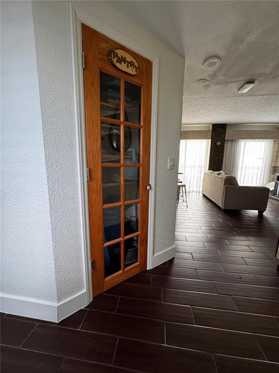 A wooden pantry door with glass panes stands next to a living room with tile flooring — 6165 CARRIER DRIVE UNIT 2702, ORLANDO, FL