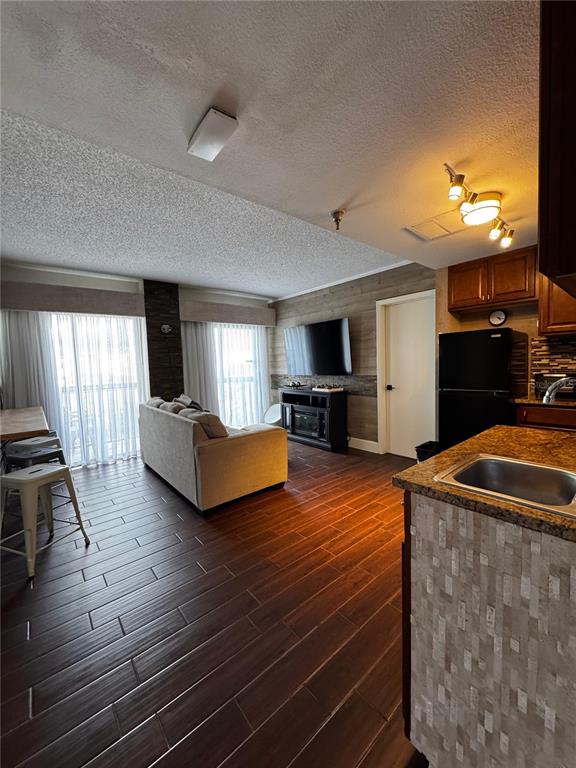 An open-concept living room and kitchen area with dark wood-look tile flooring — 6165 CARRIER DRIVE UNIT 2702, ORLANDO, FL