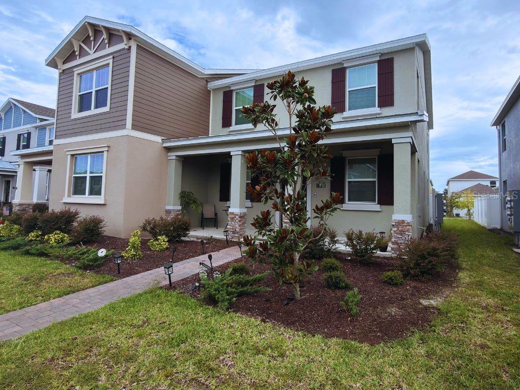 A two-story suburban house with a covered front porch, stone pillars, and a landscaped yard — 11758 BOLDFACE DRIVE, ORLANDO, FL