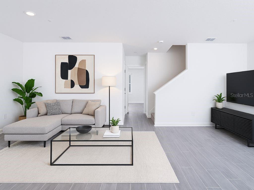 A modern living room features a gray sectional sofa, glass coffee table, and tile flooring — 11758 BOLDFACE DRIVE, ORLANDO, FL