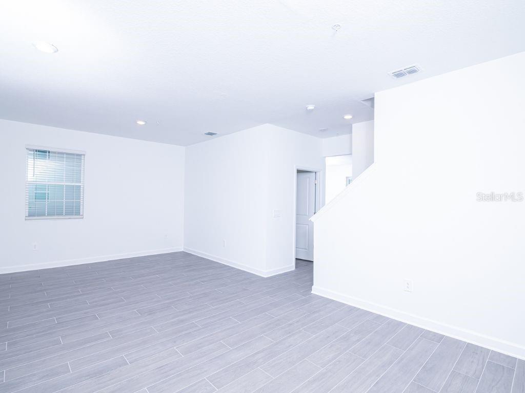 An empty room features white walls, recessed lighting, and gray wood-look tile flooring — 11758 BOLDFACE DRIVE, ORLANDO, FL