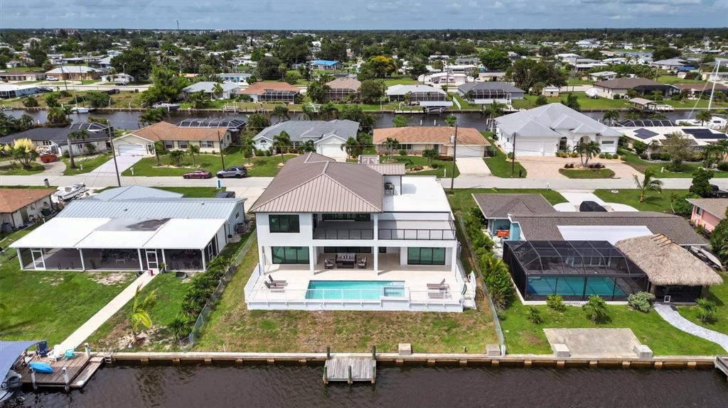 An aerial view shows a two-story waterfront house with a pool and a private dock — 133 LELAND, PORT CHARLOTTE, FL