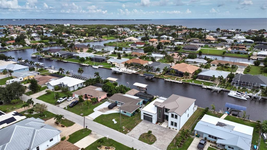An aerial view shows a residential neighborhood with houses along a canal leading to water — 133 LELAND, PORT CHARLOTTE, FL