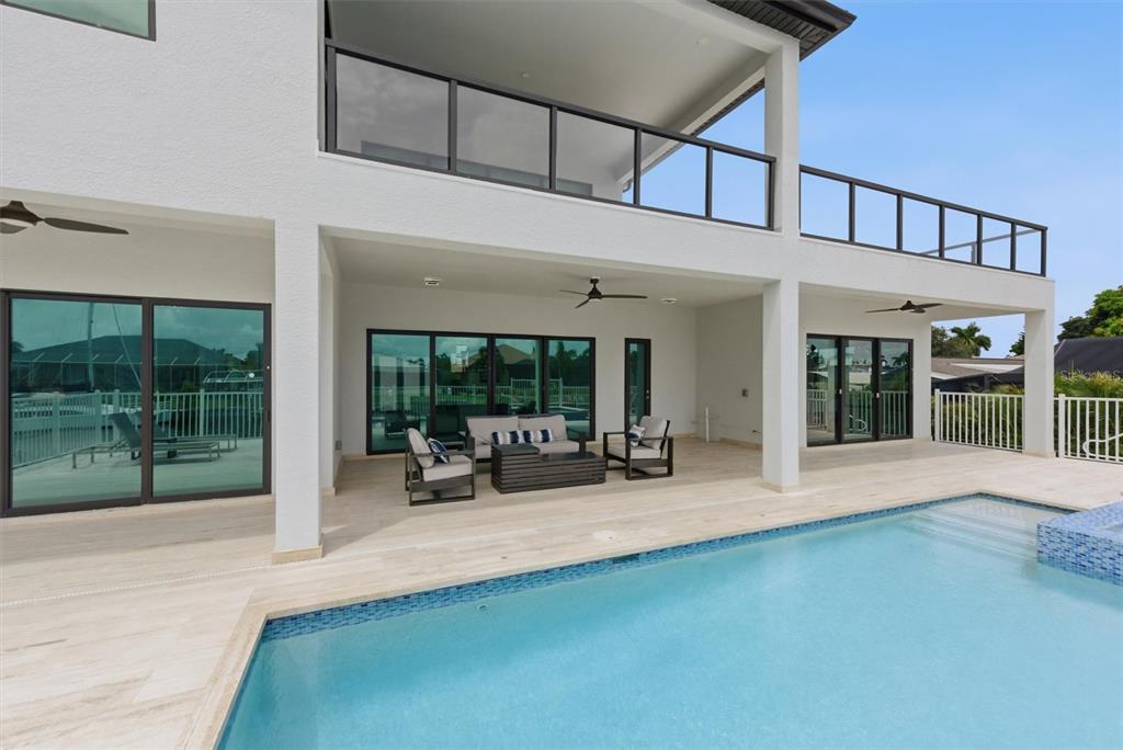 A modern two-story home exterior features a covered patio, outdoor furniture, and a swimming pool — 133 LELAND, PORT CHARLOTTE, FL