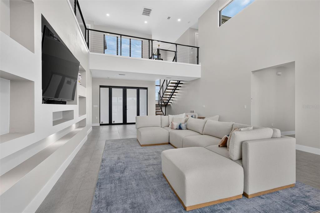 A modern living room features a large sectional sofa, a television, and a mezzanine balcony — 133 LELAND, PORT CHARLOTTE, FL