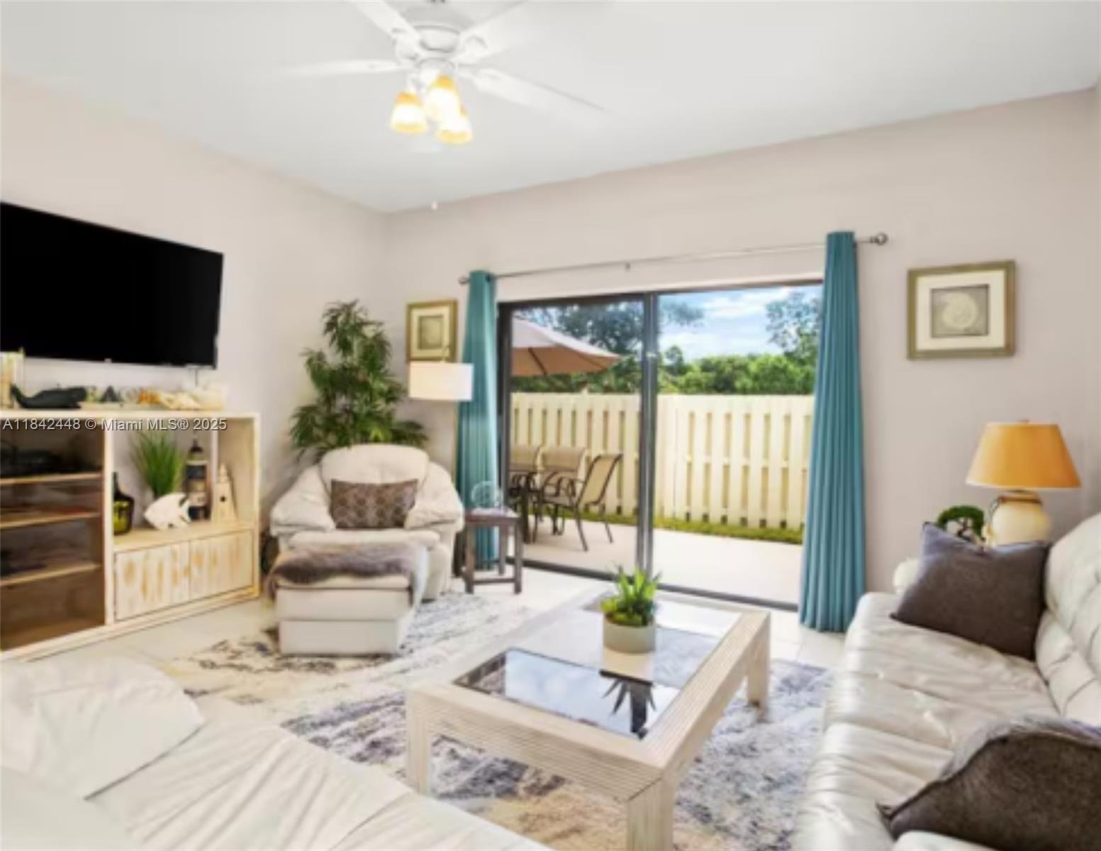 A living room features white furniture, a glass-top coffee table, and sliding doors to a patio — 720 S Bella Vista Ct S # 20, Jupiter FL 33477, JUPITER, FL