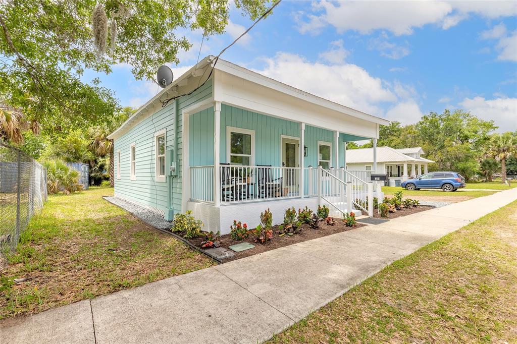 A light blue, single-story house with a front porch sits next to a sidewalk — 306 SHELDON STREET, NEW SMYRNA BEACH, FL