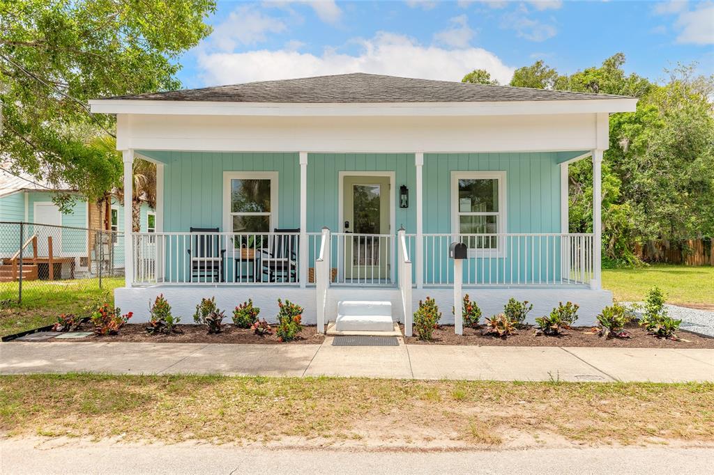 A light blue single-story house features a covered front porch with white railings and stairs — 306 SHELDON STREET, NEW SMYRNA BEACH, FL