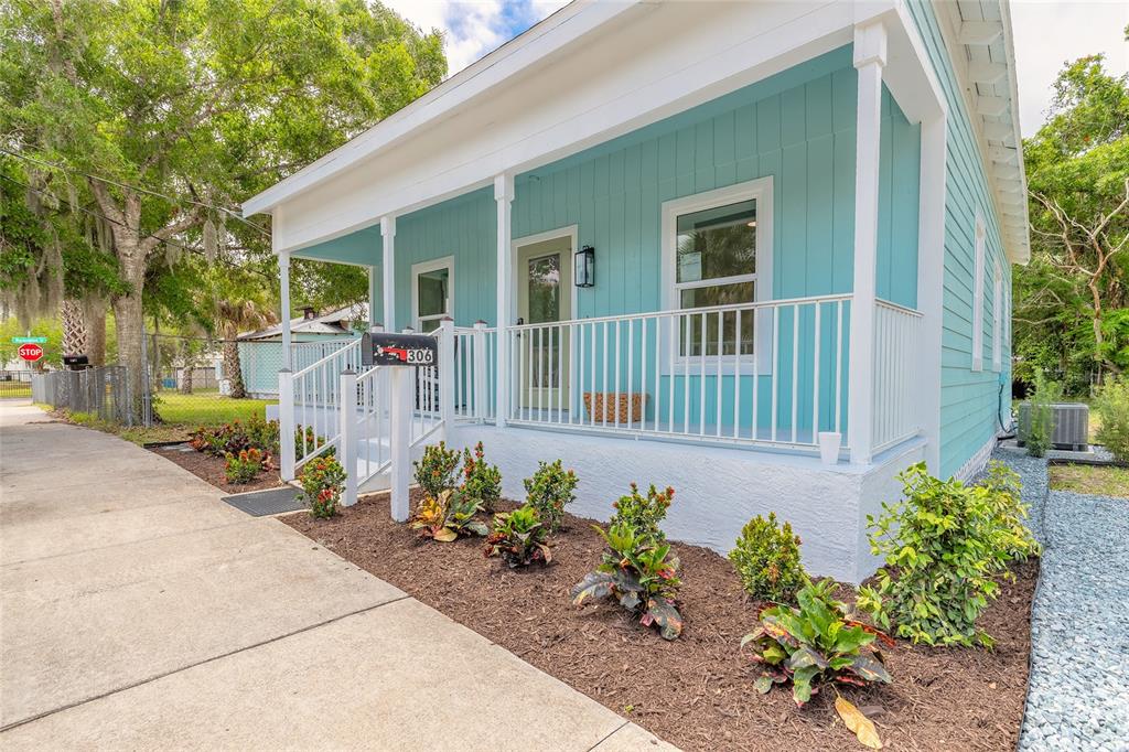 A light blue house with a front porch, white railings, and a landscaped garden bed — 306 SHELDON STREET, NEW SMYRNA BEACH, FL