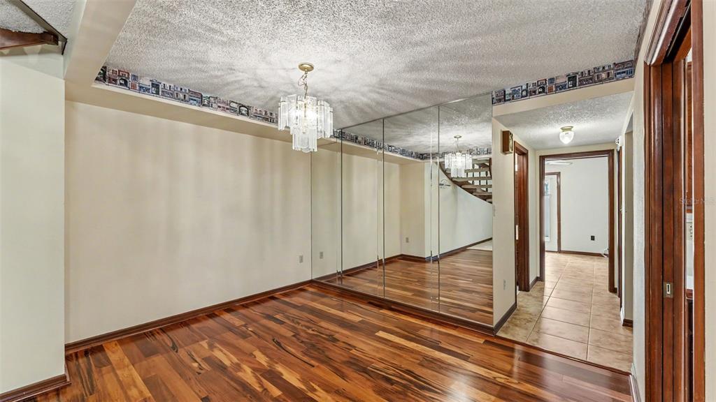 A dining room features wood flooring, a mirrored wall, a crystal chandelier, and wallpaper border — 633 VICTORIA SQUARE LANE, LAKELAND, FL