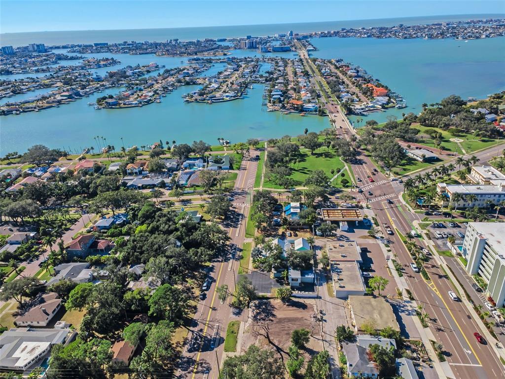 An aerial view shows a coastal neighborhood with residential homes, a park, and a bridge — 7321 1ST AVENUE S, ST PETERSBURG, FL