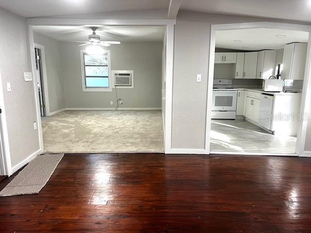 A view from a hardwood-floored room looking into a carpeted living area and a kitchen — 409 W PEARL STREET, CLERMONT, FL