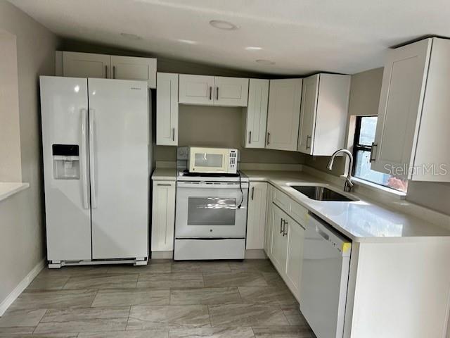 A kitchen features white cabinets, stainless steel appliances, and light-colored wood-look tile flooring — 409 W PEARL STREET, CLERMONT, FL