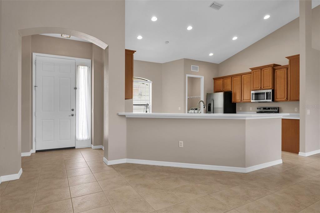 A kitchen with wood cabinets and a breakfast bar overlooks a tiled entryway — 24425 LAKEVIEW PLACE, PORT CHARLOTTE, FL