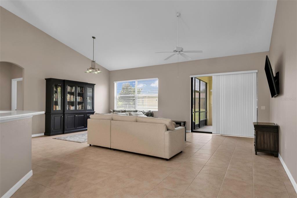 A living room features a beige sectional sofa, a black cabinet, and tile flooring — 24425 LAKEVIEW PLACE, PORT CHARLOTTE, FL