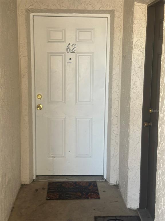 A white front door labeled 62 with gold hardware sits in a recessed entryway — 1229 KENNEDY ROAD UNIT 62, DAYTONA BEACH, FL