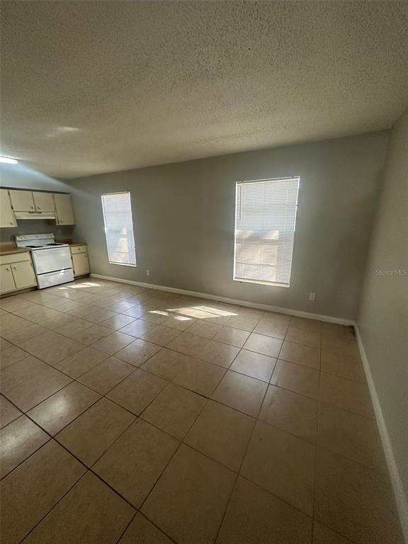 A kitchen with white cabinets, a white stove, and light-colored tile flooring — 1229 KENNEDY ROAD UNIT 62, DAYTONA BEACH, FL