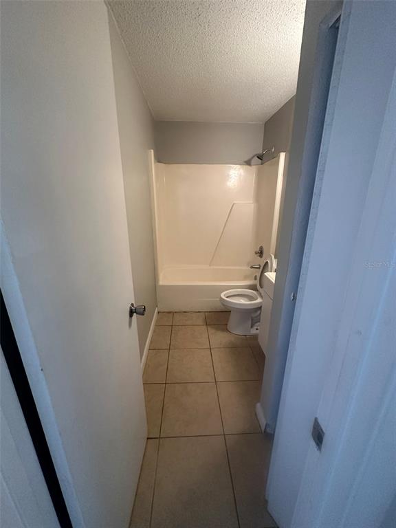 A bathroom features a beige tiled floor, a white toilet, and a shower-tub combination — 1229 KENNEDY ROAD UNIT 62, DAYTONA BEACH, FL