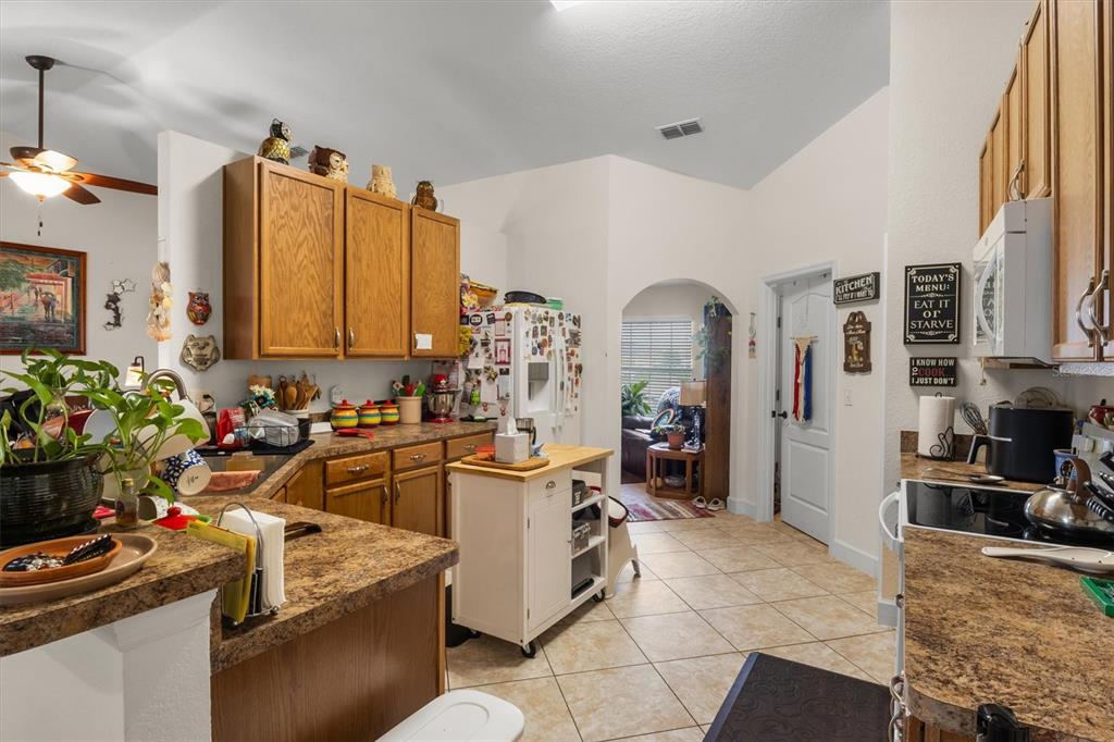 A kitchen features oak cabinets, laminate countertops, a rolling island, and tile flooring — 2559 SUNSET CIRCLE, LAKE WALES, FL