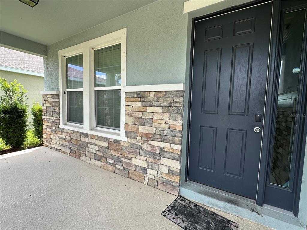 A front porch features a dark door, stone veneer siding, and two windows — 5114 JACKEL CHASE DRIVE, WIMAUMA, FL