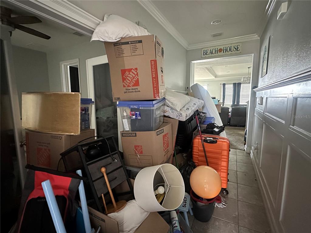 A cluttered hallway filled with moving boxes, furniture, and household items leads to another room — 5114 JACKEL CHASE DRIVE, WIMAUMA, FL