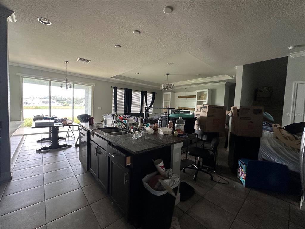 A kitchen with a dark island and granite countertops opens to a living area — 5114 JACKEL CHASE DRIVE, WIMAUMA, FL