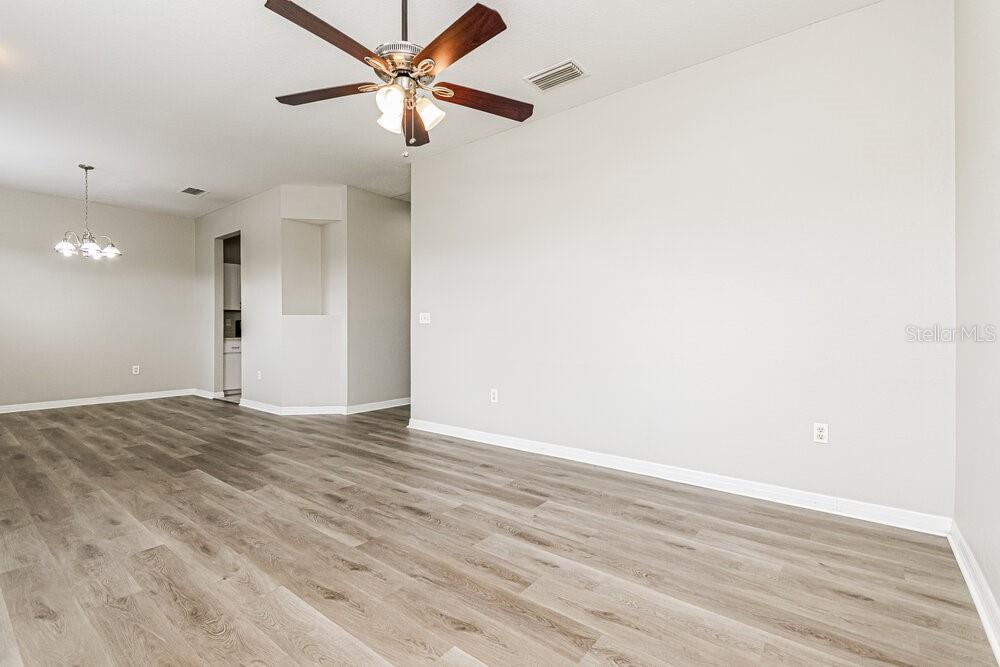 An empty room with light wood-look flooring, a ceiling fan, and a dining area light — 292 CLOVERDALE ROAD, WINTER HAVEN, FL