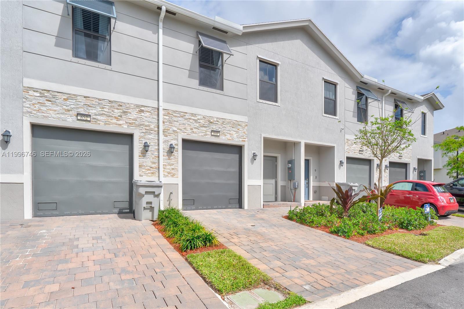 A row of two-story townhouses features gray stucco exteriors, stone accents, and paved driveways — 848 NW 3rd Ter, Pompano Beach FL 33060, POMPANO BEACH, FL
