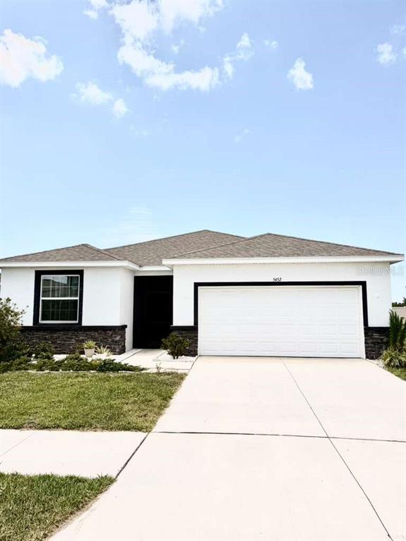A single-story house with white stucco walls, a stone base, and a two-car garage — 5452 FLINT HILLS DRIVE, WIMAUMA, FL