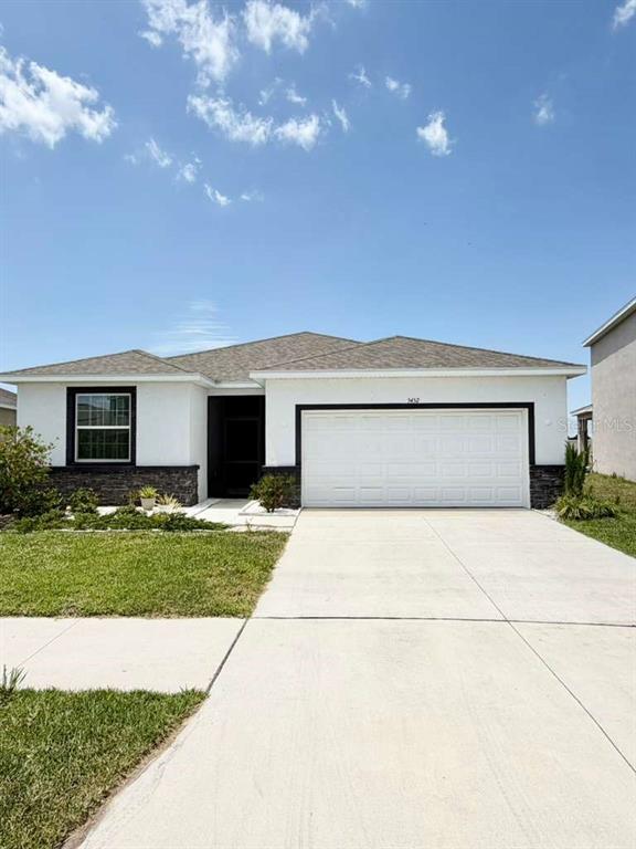 A single-story house with a white stucco exterior, stone accents, and a two-car garage — 5452 FLINT HILLS DRIVE, WIMAUMA, FL
