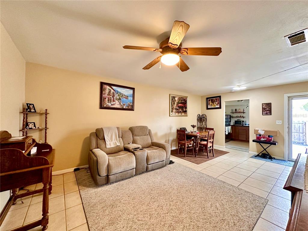 A living room with tile floors, a beige sofa, a ceiling fan, and a dining area — 712-A E ARIZONA AVENUE UNIT A, DELAND, FL
