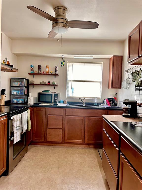 A kitchen with wood cabinets, dark countertops, a ceiling fan, and a window above the sink — 712-A E ARIZONA AVENUE UNIT A, DELAND, FL