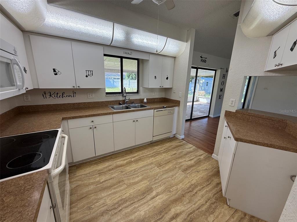 A kitchen features white cabinets, brown laminate countertops, a double sink, and wood-look flooring — 14078 SPRING HILL DRIVE, SPRING HILL, FL