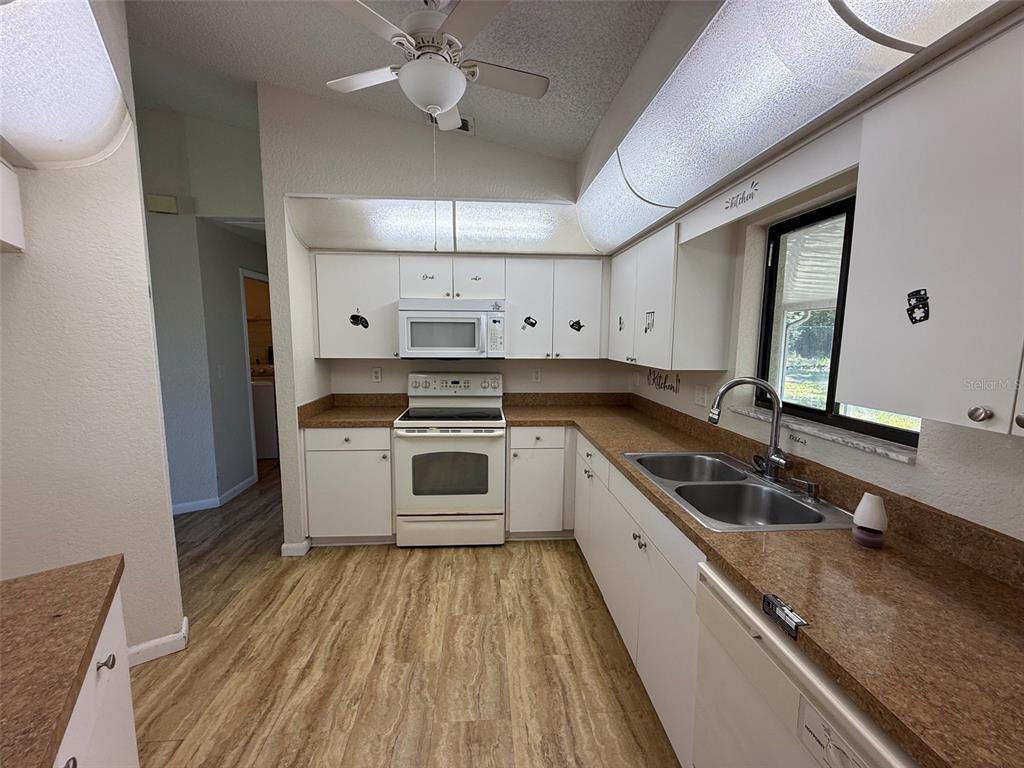 A kitchen features white cabinets, a white stove, a double sink, and brown laminate countertops — 14078 SPRING HILL DRIVE, SPRING HILL, FL
